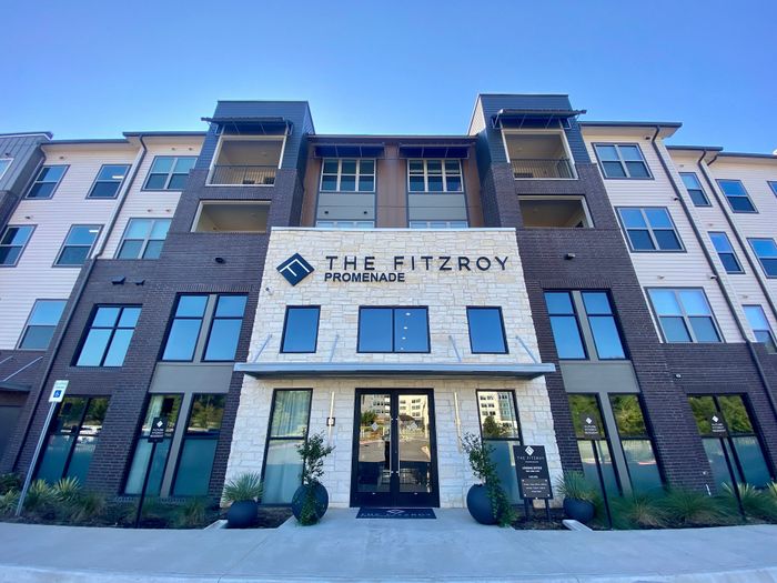 Modern apartment building front with elegant stone and brick facade, featuring stylish balconies at The Fitzroy Promenade.