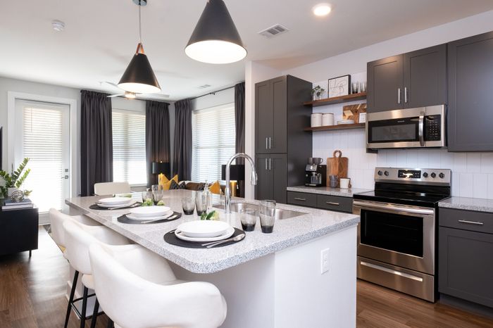 Sleek modern kitchen with stylish pendant lights, polished countertops, and elegant dining area.