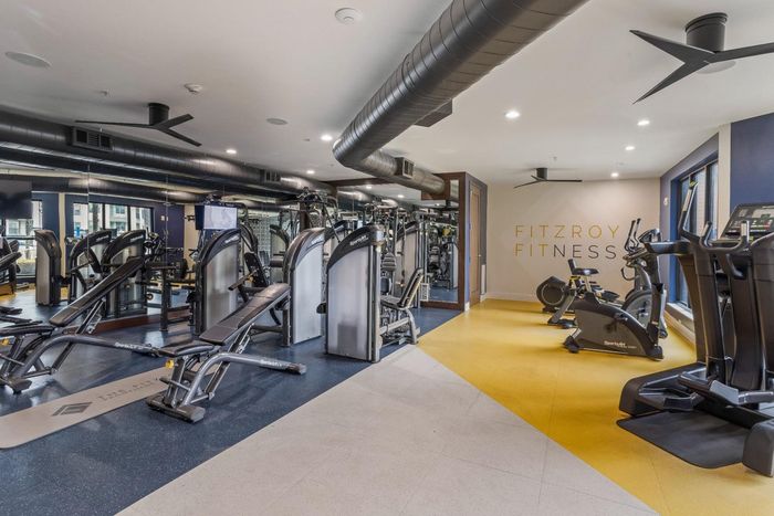 Modern fitness center at Fitzroy with state-of-the-art equipment, featuring sleek exercise machines and vibrant decor.