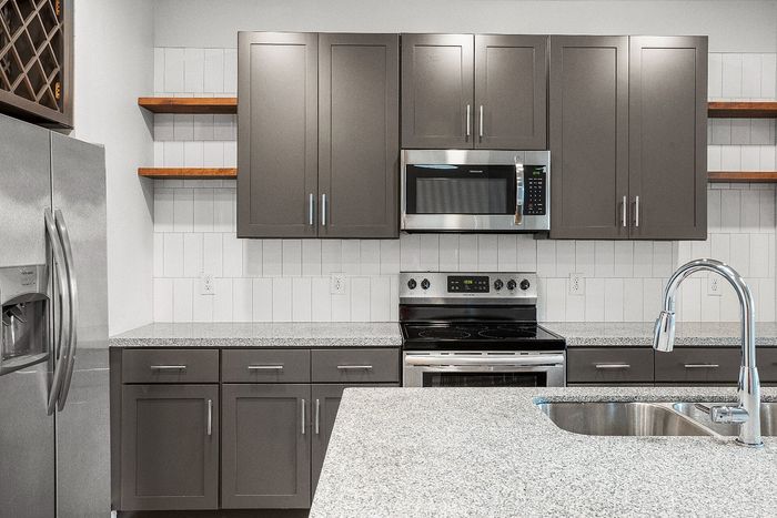 Modern kitchen with sleek stainless steel appliances, elegant gray cabinetry, and a spacious granite countertop.