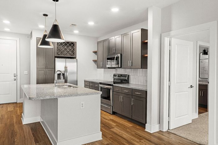 Modern kitchen with sleek cabinetry, granite countertops, stainless steel appliances, and elegant pendant lighting.