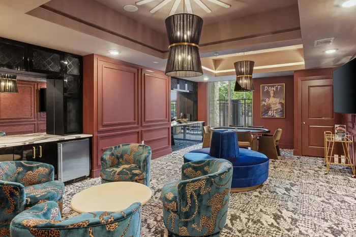 Elegant lounge area in luxurious apartment featuring chic leopard print chairs, modern lighting, and stylish decor with rich maroon accents.