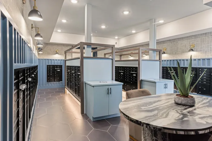 Modern and stylish mailroom featuring sleek black mailboxes, blue paneling, and elegant lighting with a chic centerpiece.