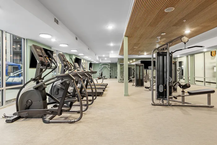 Modern fitness center with state-of-the-art exercise equipment and large windows offering natural light.