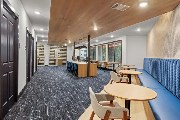 Modern communal workspace with stylish seating, natural light, and elegant wood accents, perfect for productivity.