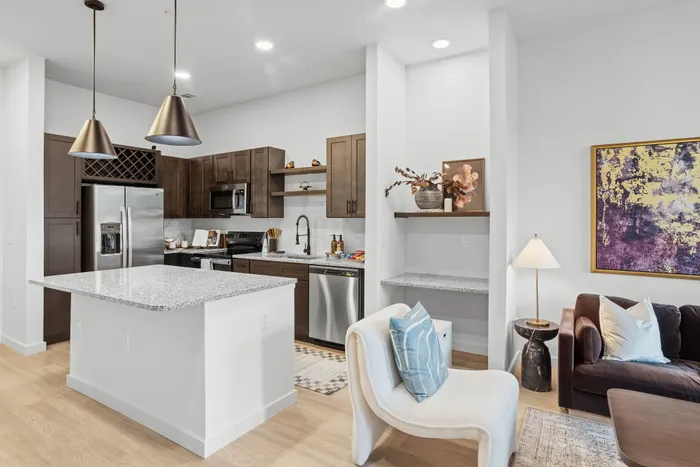 Modern open-concept kitchen and living area featuring sleek stainless steel appliances, elegant pendant lighting, and chic decor for a stylish lifestyle.