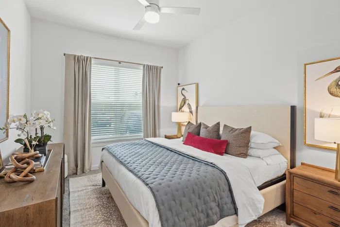 Elegant bedroom with a cozy ambiance featuring a plush bed, stylish decor, and natural light streaming through a large window.
