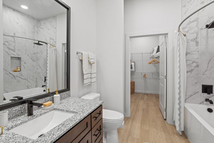 Modern and elegant bathroom featuring a marble-tiled shower, granite countertops, and a spacious walk-in closet. Perfect blend of luxury and functionality.