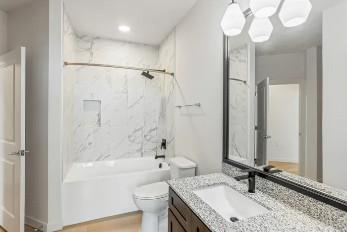Elegant bathroom featuring modern fixtures, a marble-tiled shower, and a granite countertop vanity for a luxurious living experience.