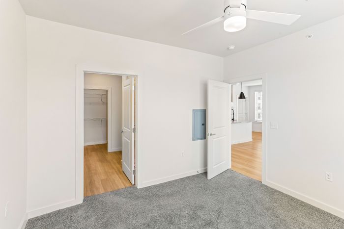 Modern bedroom with cozy carpet, spacious walk-in closet, and open access to stylish kitchen area.
