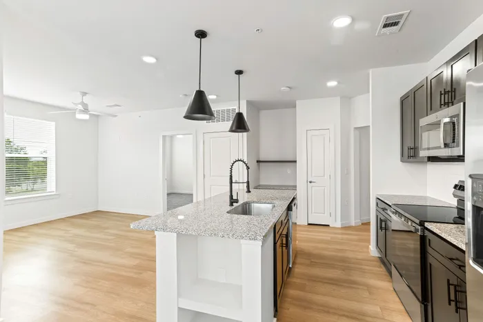 Modern kitchen with sleek granite countertops, sophisticated pendant lighting, and spacious open layout featuring hardwood floors and ample natural light.