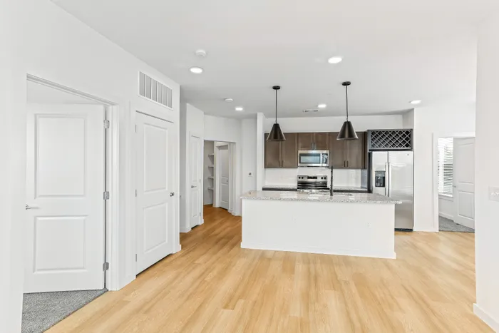 Modern open-plan kitchen with sleek granite countertops, stainless steel appliances, and elegant pendant lighting in a bright and airy apartment.