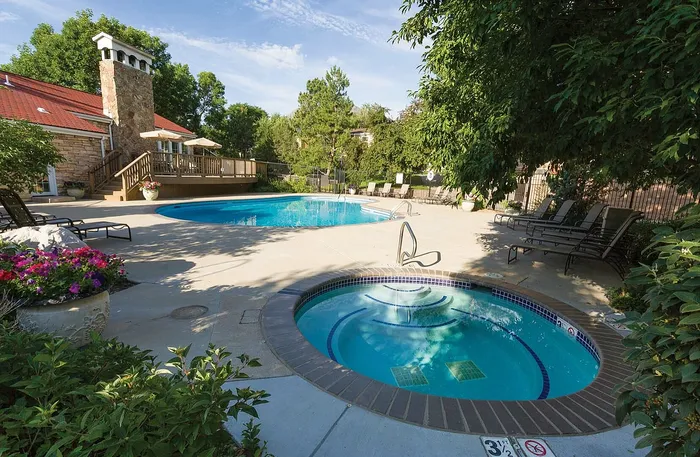 Inviting outdoor pool and spa surrounded by lush greenery and comfortable lounge chairs, perfect for relaxation and leisure.