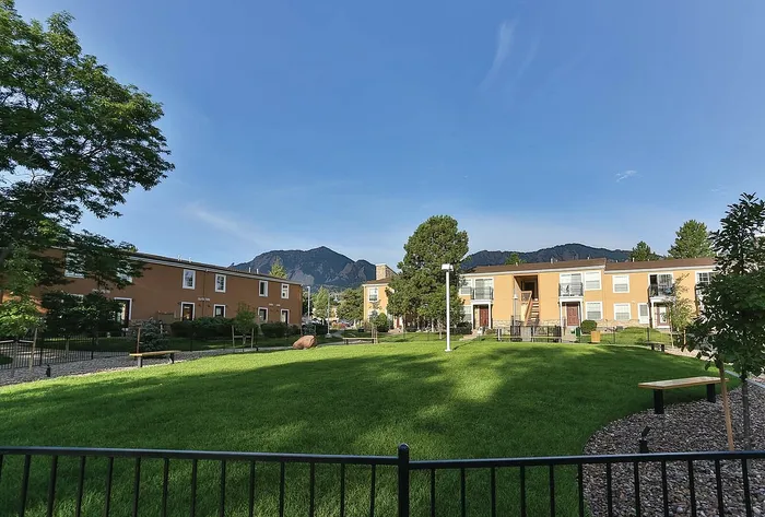 Charming apartment complex surrounded by lush green lawns and scenic mountain views.