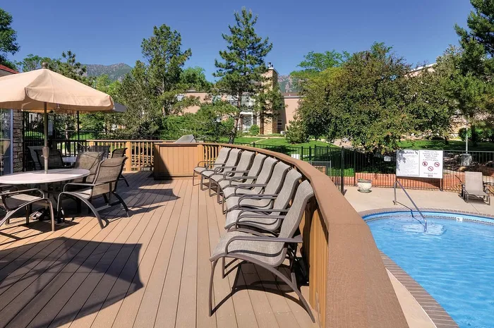 Inviting outdoor pool area with elegant lounge chairs, umbrella-covered dining, and scenic mountain views creating a serene atmosphere.