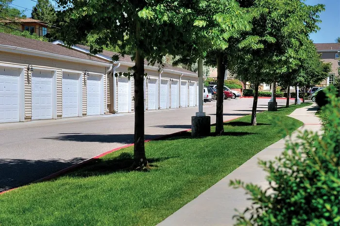 Charming apartment complex with lush greenery and convenient garages, offering a serene and practical living environment.