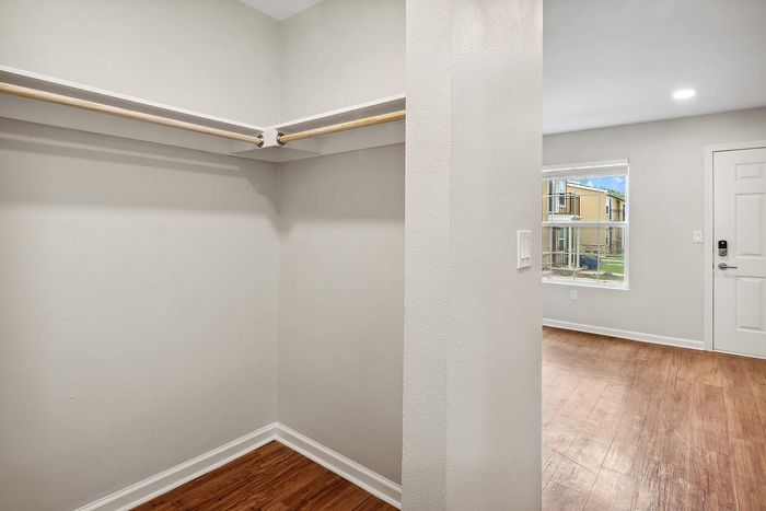 Bright and inviting apartment entryway with a spacious closet and warm hardwood floors, offering a glimpse of the serene outdoor view.