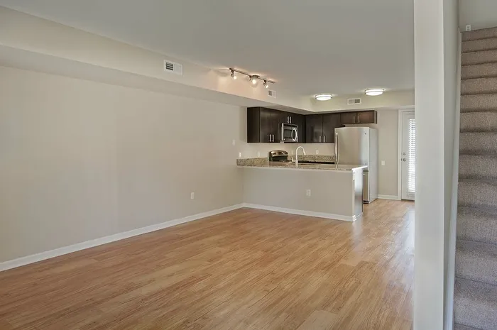 Modern open-plan kitchen and living area with elegant wood flooring and sleek stainless steel appliances.