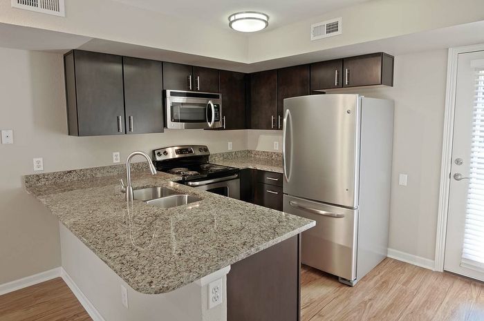 Modern kitchen with sleek granite countertops, stainless steel appliances, and rich dark cabinetry.