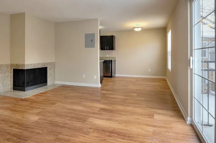 Bright and spacious open-plan living area featuring gleaming hardwood floors, a cozy fireplace, and abundant natural light from large windows.