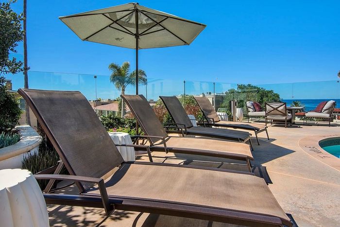 Luxurious outdoor terrace featuring elegant sun loungers, a refreshing pool, and panoramic ocean views.