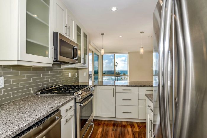 Modern beachfront kitchen with sleek stainless steel appliances, granite countertops, and stunning ocean views.