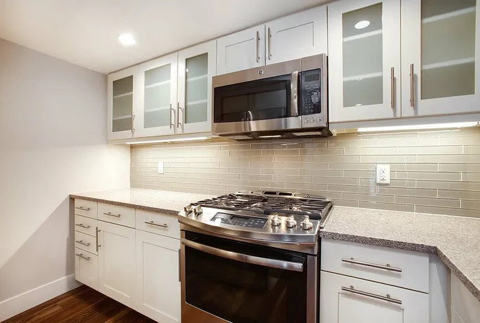 Modern kitchen with sleek stainless steel appliances, granite countertops, and elegant glass-front cabinets.