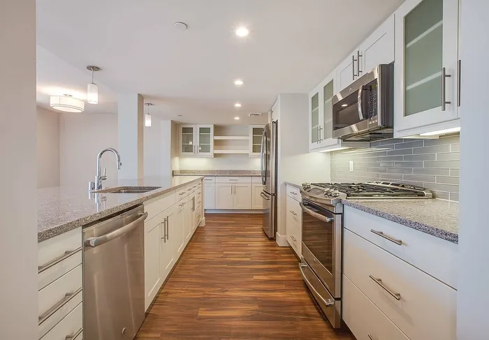 Elegant kitchen with sleek stainless steel appliances, modern cabinetry, and stylish hardwood flooring illuminated by soft overhead lighting.