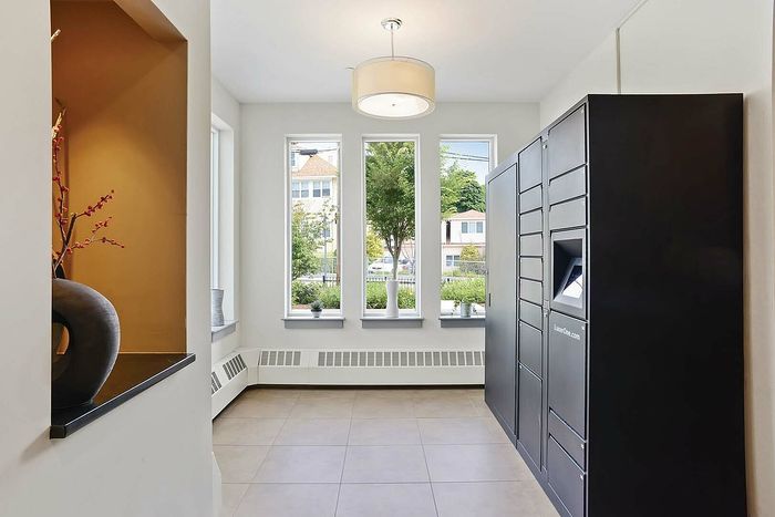 Elegant lobby area with large windows offering abundant natural light, sleek modern locker system, and contemporary vase decor.