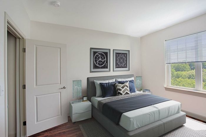 Bright and airy bedroom with modern decor, featuring a cozy bed, sleek side tables, and large sunlit window with a green view.