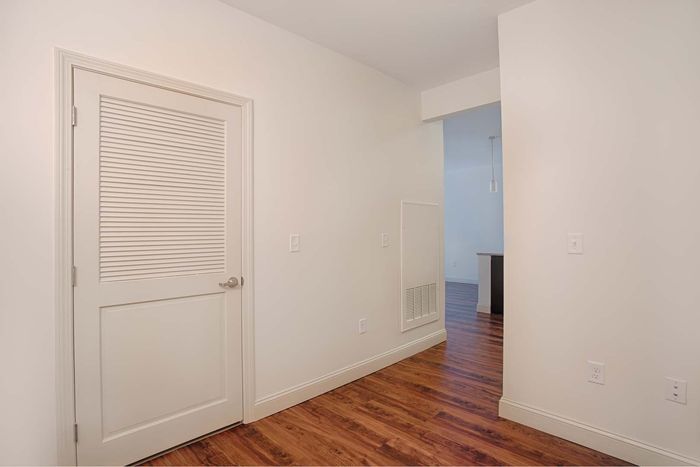 Inviting entryway with warm wood flooring, modern white door, and sleek pendant lighting.