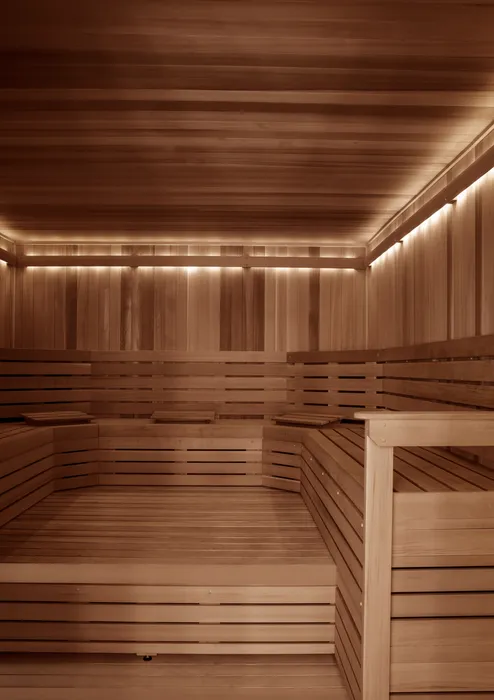 Luxurious wooden sauna room with warm lighting and spacious seating, promising relaxation and comfort.