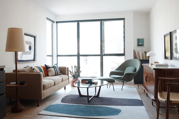 Bright, modern living room with stylish decor featuring a cozy sofa, chic armchair, and floor-to-ceiling windows offering abundant natural light.