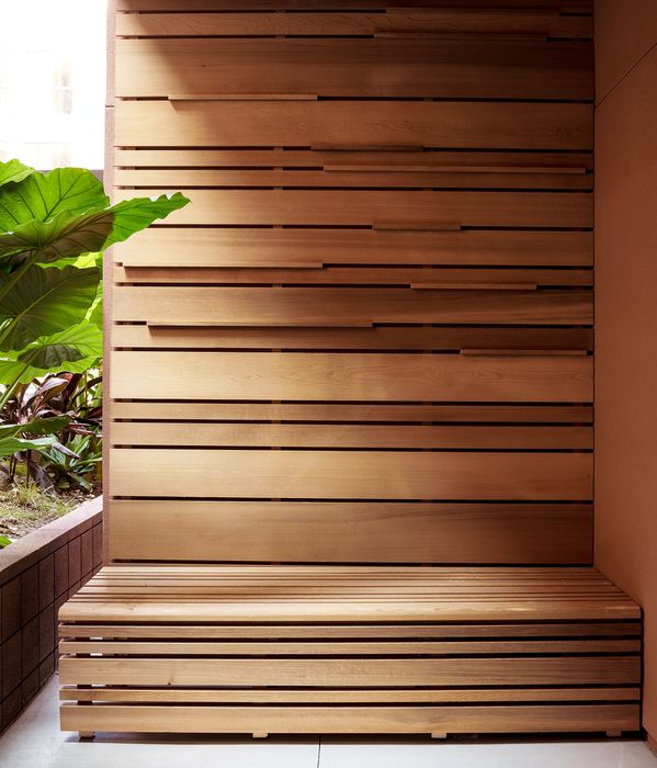 Contemporary wooden bench with slatted design surrounded by lush green plants, creating a serene and stylish outdoor living space.