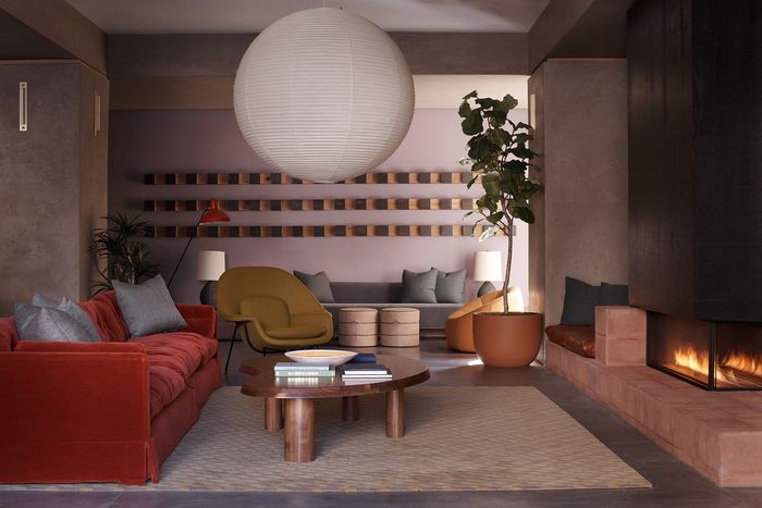 Chic living room with modern red sofa, stylish chairs, and a warm fireplace, creating a cozy and inviting atmosphere.