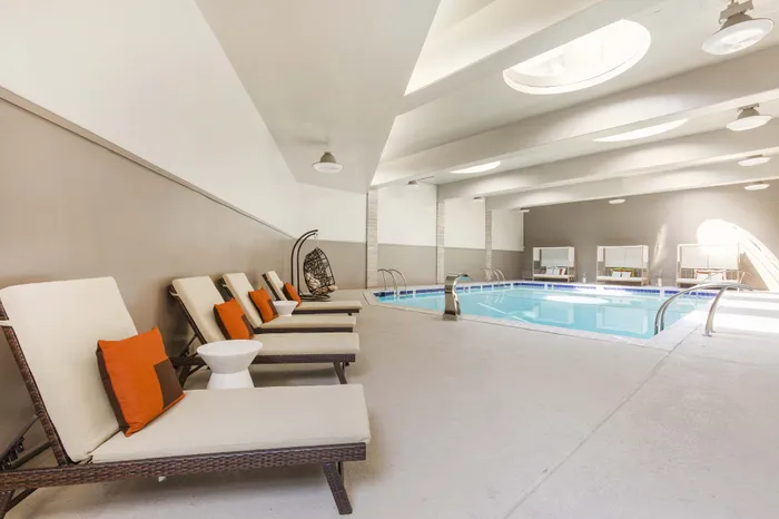 Luxurious indoor pool area with stylish lounge chairs and modern accents, perfect for relaxation and leisure.