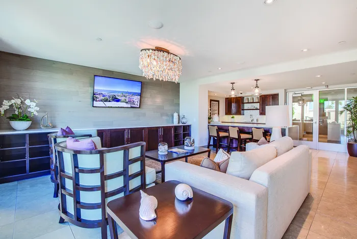 Luxurious open-concept living room with elegant lighting, cozy seating, and modern kitchen with high-end finishes.