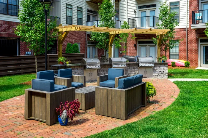 Charming outdoor patio featuring comfortable seating, modern grills, and lush greenery in a stylish communal space.