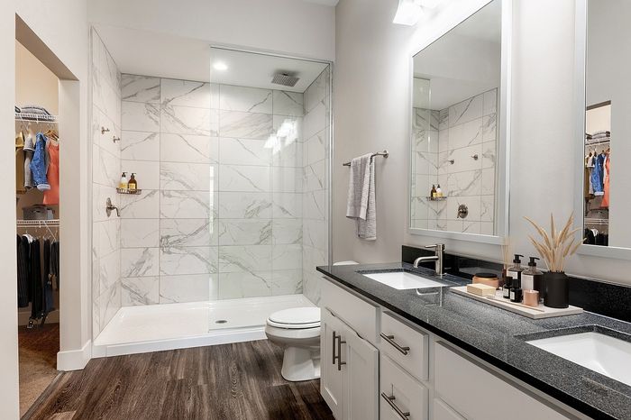 Luxurious bathroom with sleek marble tiles, modern double sink vanity, and a spacious walk-in shower.