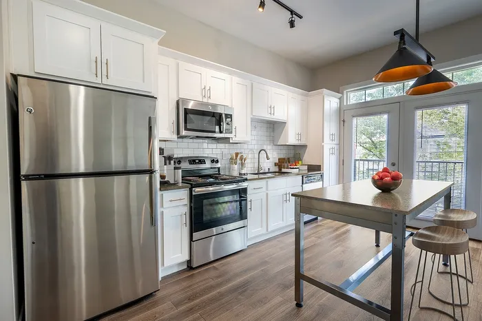 Modern kitchen with sleek stainless steel appliances, chic white cabinetry, and a stylish island featuring trendy wooden stools.