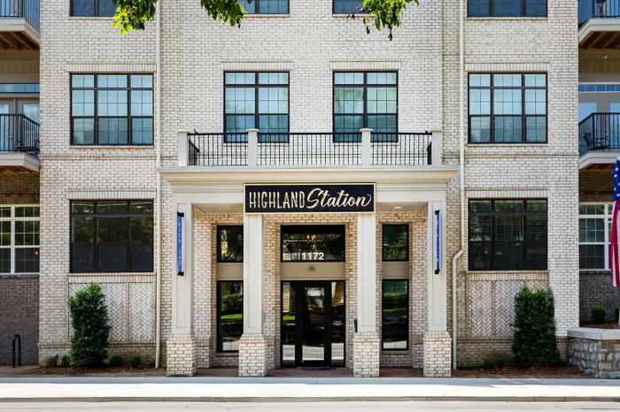 Charming apartment exterior featuring elegant brickwork and large windows, inviting entrance at Highland Station.