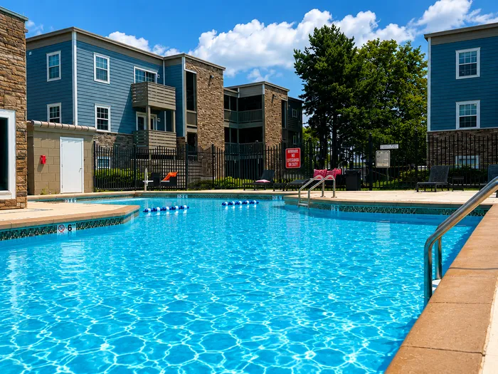 Inviting outdoor pool area surrounded by modern apartment buildings and lush greenery, perfect for relaxation and leisure in a vibrant community.