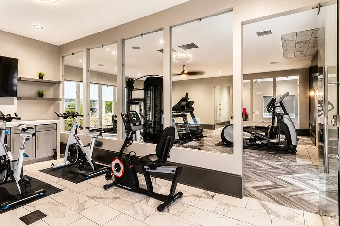 Modern gym with sleek exercise bikes and state-of-the-art equipment, offering a bright and inviting workout space with mirrored walls and contemporary design.