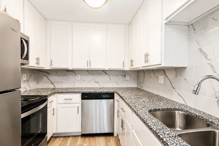 Sleek modern kitchen with stylish granite countertops, white cabinetry, stainless steel appliances, and elegant tile backsplash.
