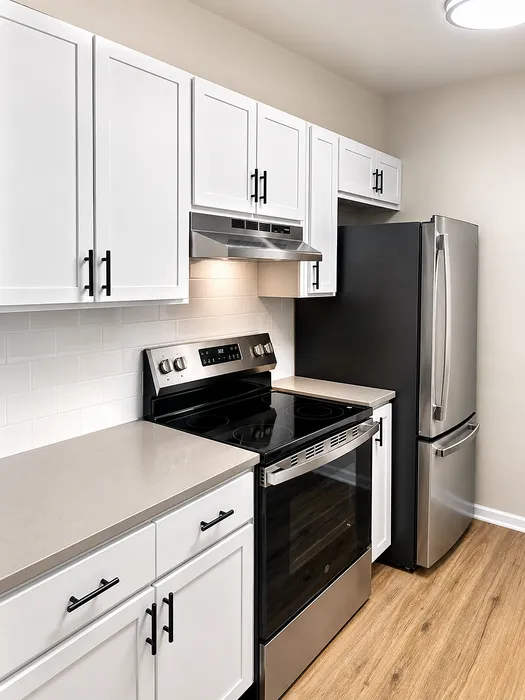 Modern kitchen with sleek stainless steel appliances, elegant white cabinetry, and a stylish wood floor.