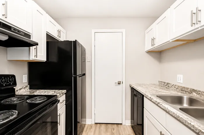 Modern kitchen with sleek black appliances, granite countertops, and stylish white cabinetry.