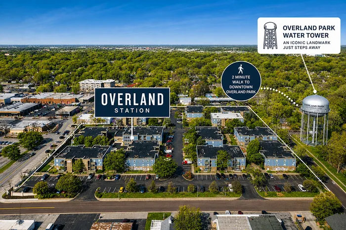 Aerial view of Overland Station apartments surrounded by lush greenery, with a prominent water tower nearby, showcasing a vibrant community just a 2-minute walk from downtown Overland Park.