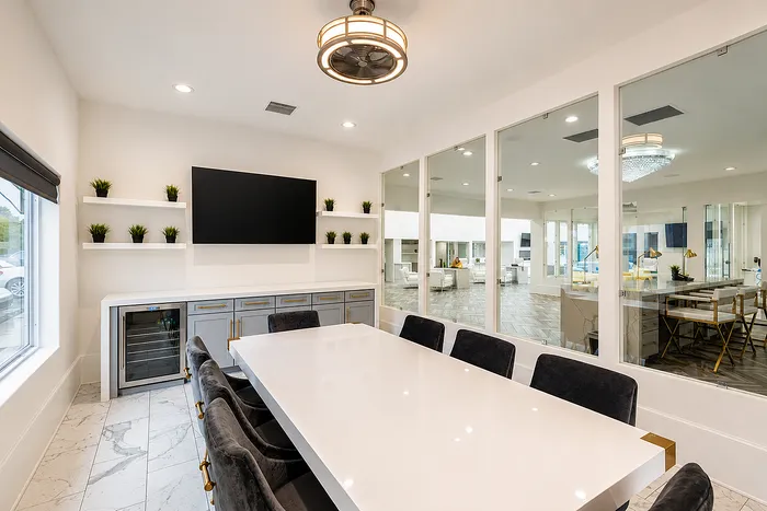 Modern communal space with elegant table, plush chairs, built-in shelves, and large TV, perfect for meetings or gatherings.