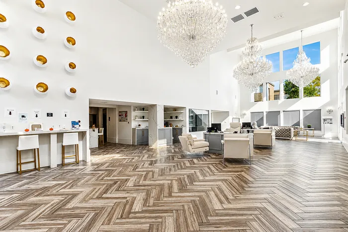 Luxurious, bright apartment lobby with elegant chandeliers, modern decor, and expansive windows offering natural light.