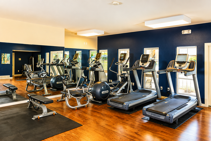 Modern apartment gym with state-of-the-art equipment, mirrored walls, and vibrant blue accents offers an inviting workout space.